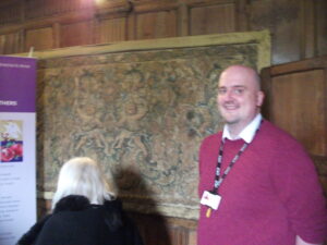 Dr Owen Emmerson in front of a tapestry